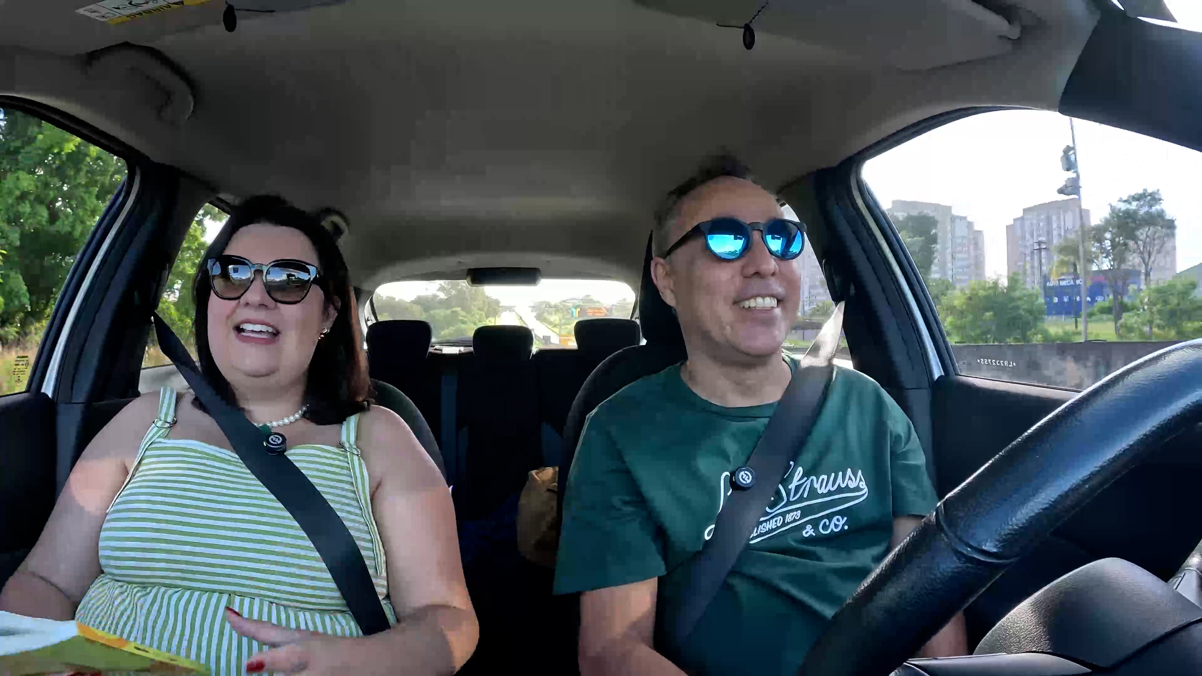 Helo e Neto sorrindo dentro do carro, com Neto ao volante